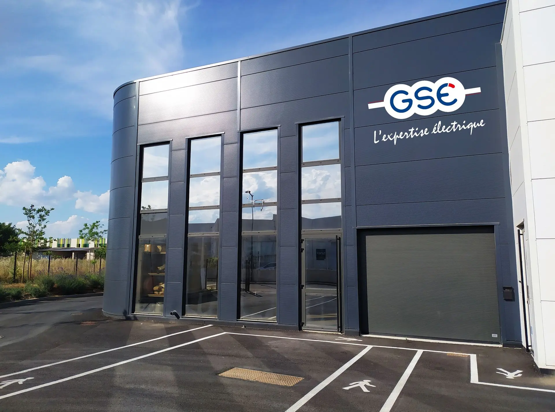 Vue des bureaux de GSE, bâtiment moderne gris anthracite avec une façade vitrée. Belle exposition ensoleillée qui donne envie de venir nous voir !